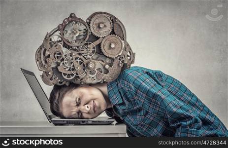 Under pressure of work. Woman programmer pressed with engine mechanism to laptop