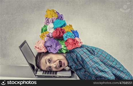 Under pressure of work. Woman programmer pressed with paper balls to laptop