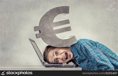 Under pressure of work. Woman programmer pressed with stone euro sign to laptop