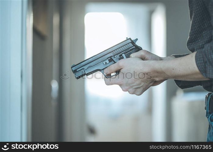 Undercover police agent is holding a black weapon in his hand, ready for shoot