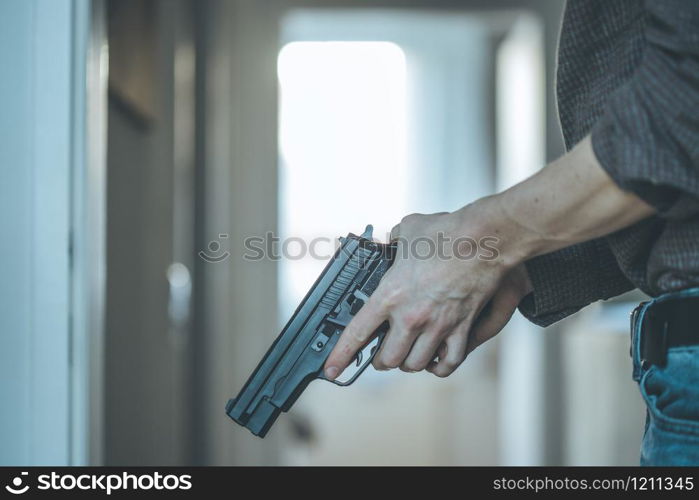 Undercover police agent is holding a black weapon in his hand, ready for shoot