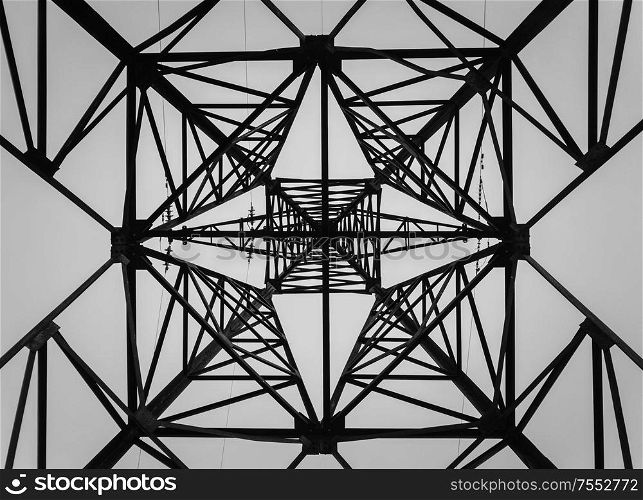 Underneath a truss pillar construction. Different geometric shapes, patterns of a steel structure. Metallic texture of an electricity pole.
