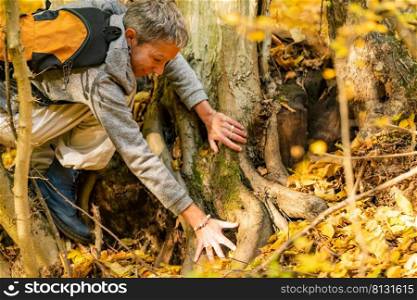 Understanding the beginnings. Mindful, middle-aged woman reaching towards the tree roots in the ground. Conceptual image . Understanding the beginnings. Mindful, middle-aged woman reaching towards the tree roots in the ground. Conceptual image