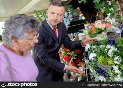 Undertaker helping woman choose flowers
