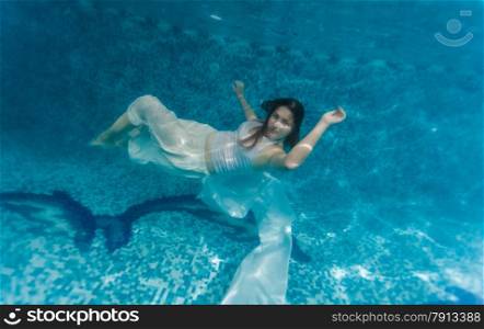 Underwater shot of woman in white cloth swimming underwater