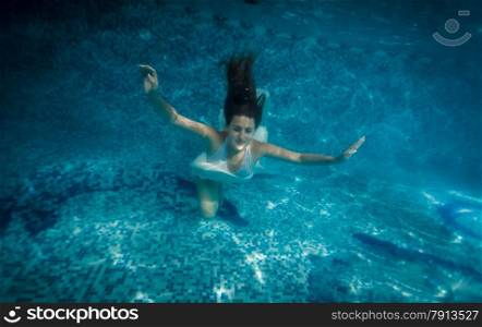 Underwater shot of woman with long hair swimming at pool