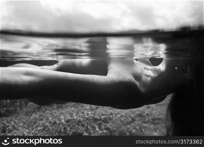 Underwater view of young Asian nude woman floating on back.