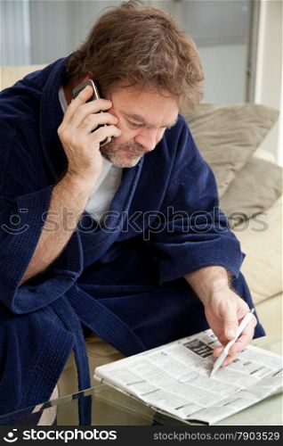 Unemployed man looking through the job listings and making phone calls.