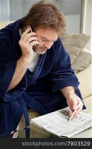 Unemployed man looking through the job listings and making phone calls.