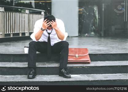 Unemployed Tired or stressed businessman sitting on the walkway after work Stressed businessman concept
