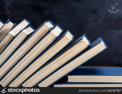 uneven pile of books in the blue cover, black background, copy space