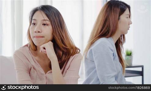 Unhappy Asian lesbian lgbt couple sitting each side of sofa with moody emotion in living room. Women conflict with her girlfriend and have bad relationship at home.