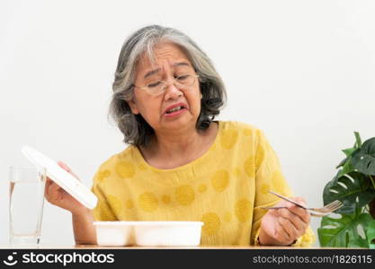 Unhappy Asian senior woman anorexia and say no to ready meals, Elderly home alone and bored food and no appetite