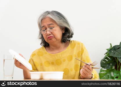 Unhappy Asian senior woman anorexia and say no to ready meals, Elderly home alone and bored food and no appetite