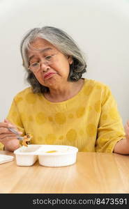 Unhappy Asian senior woman anorexia and say no to ready meals, Elderly home alone and bored food and no appetite