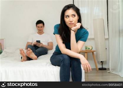 Unhappy Asian woman in bed and feeling Bored and grumpy her husband because tired of her husband who ignores her and uses the smartphone all time. Concept of relationship problem from technology