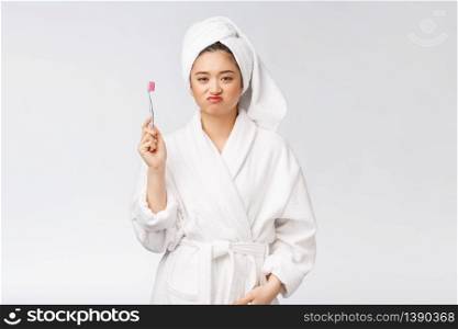 Unhappy beautiful woman brushing her teeth on white background.. Unhappy beautiful woman brushing her teeth on white background