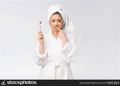 Unhappy beautiful woman brushing her teeth on white background.. Unhappy beautiful woman brushing her teeth on white background