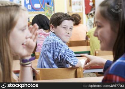 Unhappy Boy Being Gossiped About By School Friends In Classroom