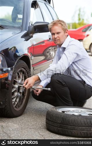 Unhappy business man replacing tire on car