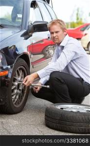 Unhappy business man replacing tire on car