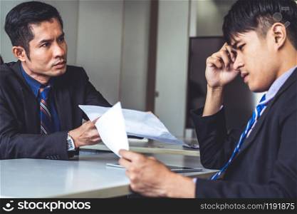 Unhappy business manager and young businessman partner in meeting room at the office. They are under stress because of bad financial document report. Company crisis concept.