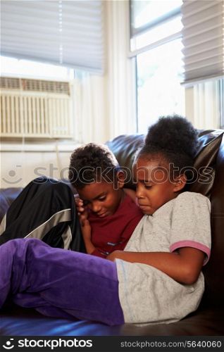 Unhappy Children Sitting On Sofa At Home