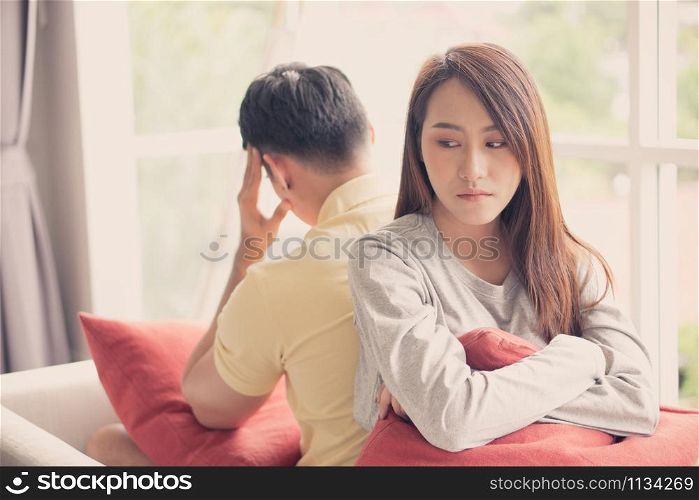 Unhappy Couple sitting behind each other on the couch and avoid talking or looking at each other, Cause of relationship problems and having misunderstanding or disagreement. Family problems concept
