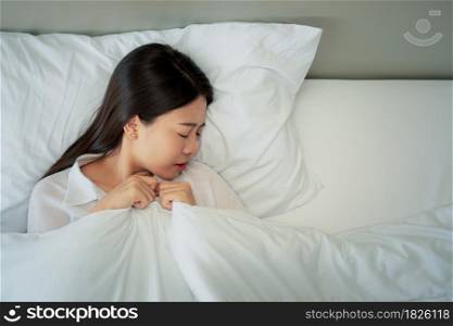 Unhappy exhausted woman closed eyes lying in bed cause of Headache, sore throat and tired, Concept of recuperation from illness, feeling unwell and healthcare.