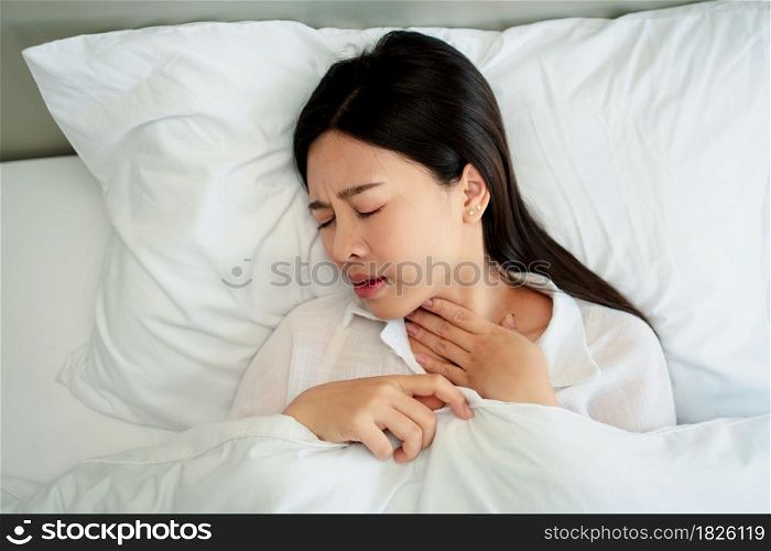 Unhappy exhausted woman closed eyes lying in bed cause of Headache, sore throat and tired, Concept of recuperation from illness, feeling unwell and healthcare.
