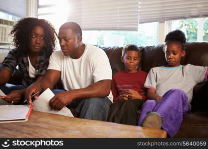 Unhappy Family Sitting On Sofa Looking At Bills