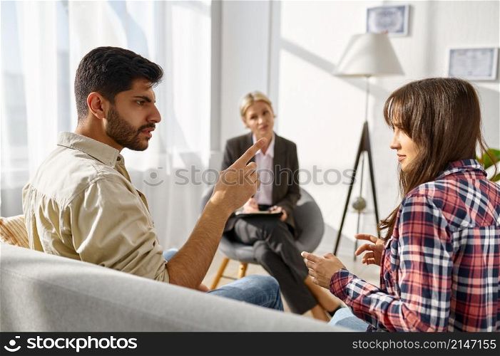 Unhappy frustrated couple arguing discussing relationship problems at psychologists office. Unhappy couple arguing disagreement at psychologists office