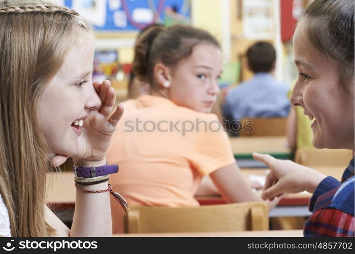 Unhappy Girl Being Gossiped About By School Friends In Classroom