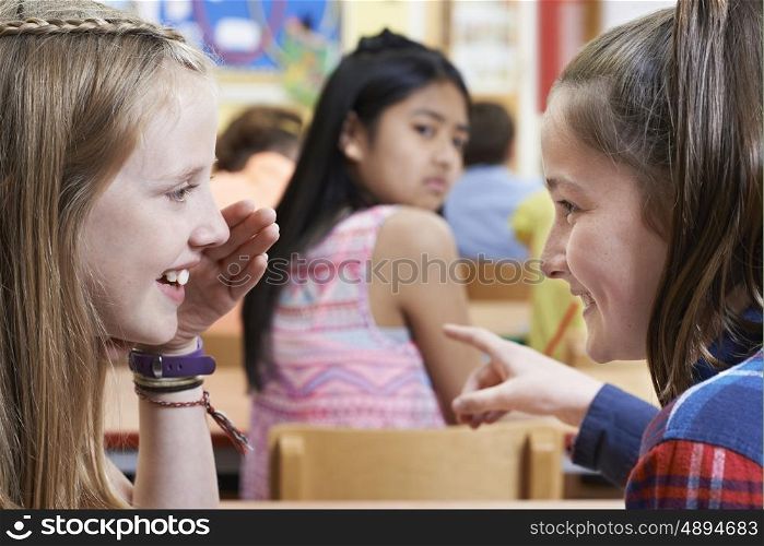 Unhappy Girl Being Gossiped About By School Friends In Classroom