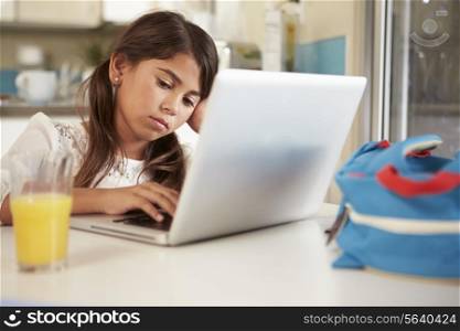 Unhappy Hispanic Girl Using Laptop To Do Homework At Table