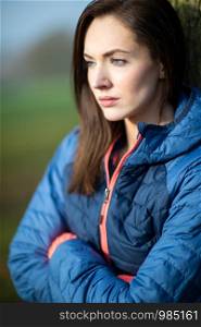 Unhappy Looking Young Woman Leaning Against Tree On Winter Walk In Park