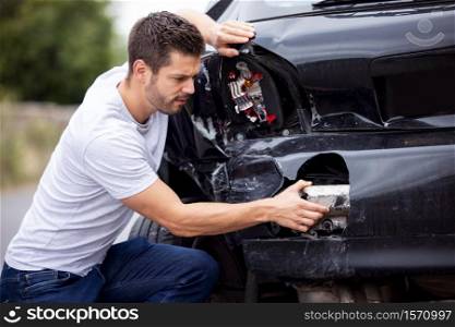 Unhappy Male Driver Inspecting Damaged Car After Accident