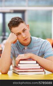 Unhappy Male Student Studying In Classroom With Books