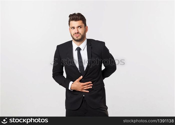 Unhappy man with stomach pain spasm. portrait of handsome bearded businessman in suit. Indoor studio shot, isolated on grey background.. Unhappy man with stomach pain spasm. portrait of handsome bearded businessman in suit. Indoor studio shot, isolated on grey background
