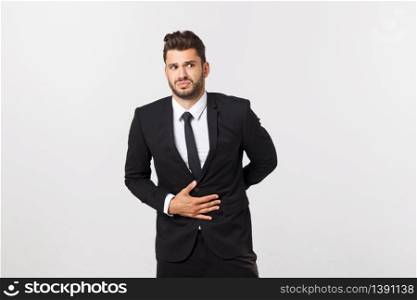 Unhappy man with stomach pain spasm. portrait of handsome bearded businessman in suit. Indoor studio shot, isolated on grey background.. Unhappy man with stomach pain spasm. portrait of handsome bearded businessman in suit. Indoor studio shot, isolated on grey background