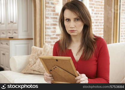 Unhappy Mature Woman Looking At Photograph In Frame