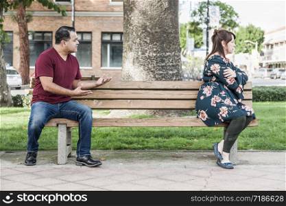 Unhappy Mixed Race Couple Sitting Facing Away From Each Other on Park Bench.