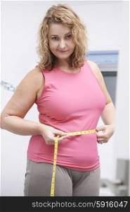 Unhappy Overweight Woman Measuring Waist In Bathroom