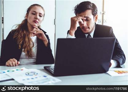 Unhappy serious businessman and businesswoman working using laptop computer on the office desk. Bad business crisis situation and bankruptcy concept.