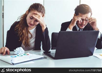 Unhappy serious businessman and businesswoman working using laptop computer on the office desk. Bad business crisis situation and bankruptcy concept.