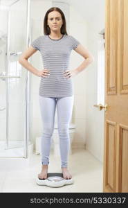Unhappy Teenage Girl Standing On Bathroom Scales