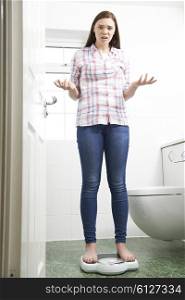 Unhappy Teenage Girl Standing On Bathroom Scales