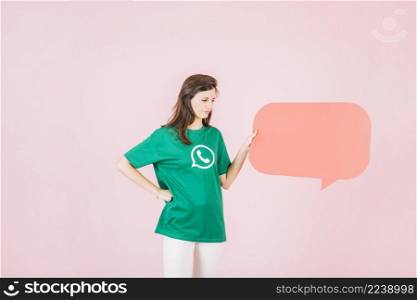 unhappy woman holding empty orange speech bubble pink background