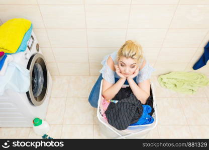 Unhappy woman in bathroom with big basket of dirty clothes. Laundry concept. Household duties.. Unhappy girl with dirty clothes laundry.