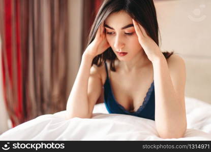 Unhappy woman in depression sits in bed under the blanket, female stress concept. Emotional stressed girl having a problem. Woman in depression sits in bed under the blanket